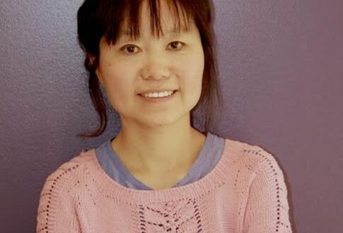 Smiling woman in pink sweater against purple wall